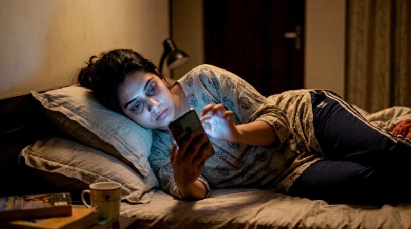 Young woman using phone late at night in dark room showing smartphone addiction and screen light glow